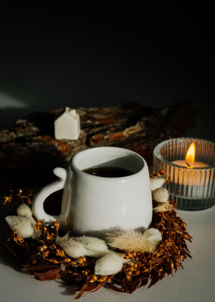 A warm and inviting still life of coffee, candle, and decor for relaxation.