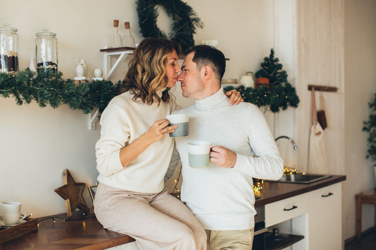 Romantic couple enjoying coffee together in a festive kitchen during Christmas.