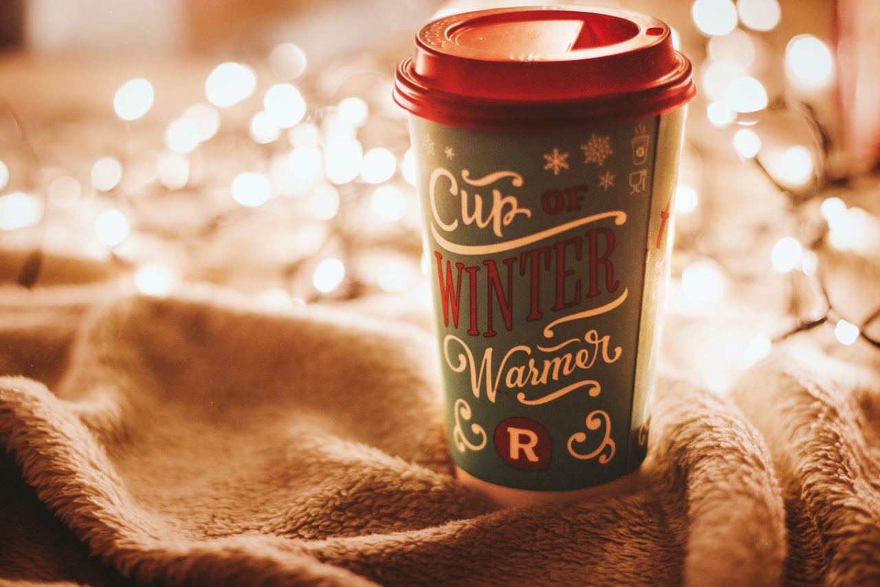 Cozy winter coffee cup with bokeh fairy lights creates a warm and festive atmosphere.